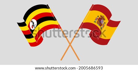 Crossed and waving flags of Uganda and Spain