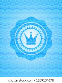 crown icon inside sky blue water wave badge.