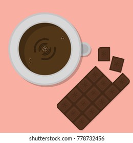 
a cup of coffee on a table with a chocolate bar