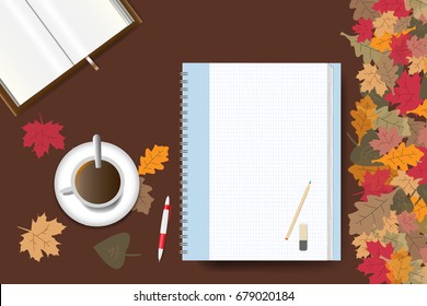 Cup of coffee, part of an open book and a blank notepad ready for your text are lying on a brown wooden table. The edge forms colorful autumn leaves.