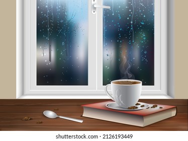 A cup of coffee, a spoon and scattered coffee beans next to a book on a wooden table by a window splashed with raindrops in an early rainy morning or late evening. 