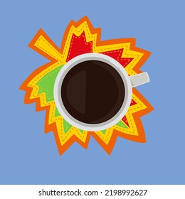 A cup of coffee stands on a bright autumn leaf. Decorative autumn leaf made of fabric.