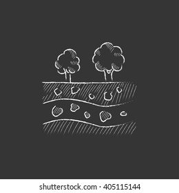Cut of soil with different layers and trees on top. Drawn in chalk icon.