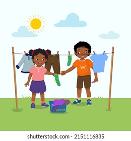 Cute African kids doing laundry chore hanging wet clothes outside under sunlight to dry on the backyard