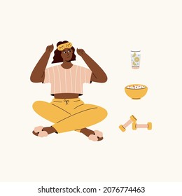 Cute afro american girl with sleeping mask and elements for morning routine: lemon water, weights, muesli. Girl thing about how to start her day. Woman in cute pajama.