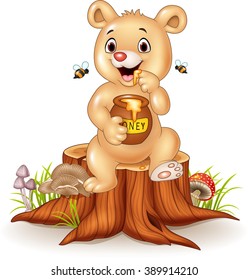 Cute baby bear holding honey pot on tree stump