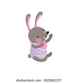 Cute baby rabbit sitting isolated on white. Adorable forest animal with long ears dressed in children clothes. Cartoon bunny character. Flat vector design
