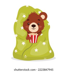 A cute bear wrapped himself in a blanket with popcorn.