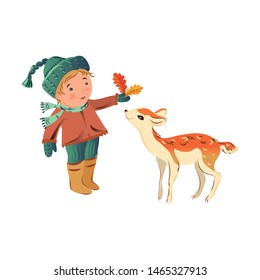 Cute blonde hair boy is given leaves to roe deer