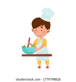 Cute Boy Character in Hat and Apron Standing at Kitchen Table and Stirring Salad Vector Illustration