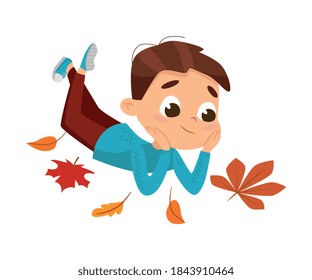 Cute Boy Lying on Ground Surrounded by Colorful Leaves, Happy Kid Playing Outdoors in Autumn Cartoon Style Vector Illustration
