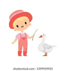 Cute Boy in Overalls, Rubber Boots and Hat Grazing Goose, Young Farmer Cartoon Character Engaged in Agricultural Activities Vector Illustration