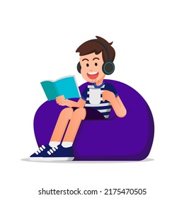 Cute Boy Reading A Book And Using A Headset While Sitting On A Beanbag