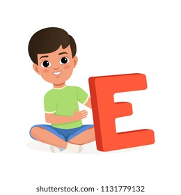 Cute boy sitting with crossed legs and holding big letter E. Cartoon character of little kid. Fun educational game. Flat vector design