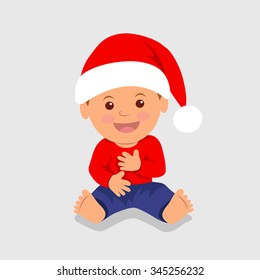 Cute boy sitting in the red Santa hat and laughs