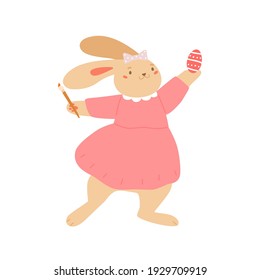 Cute bunny holding brush and painting egg for Easter. Funny baby rabbit standing in dress. Colored flat vector illustration isolated on white background