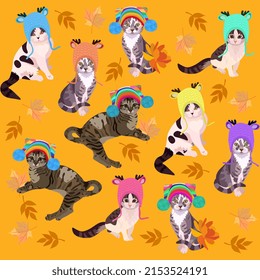 Cute cartoon cats in knitted hats with pom-poms play with autumn leaves isolated on a marigold-colored orange background. Seamless print for fabric, wallpaper, excellent textile for children's jacket.