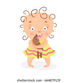 Cute cartoon curly baby girl in yellow dress playing with teddy bear colorful character vector Illustration