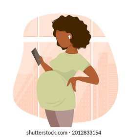 Cute cartoon dark skinned pregnant woman in pants and t-shirt listens to music with headphones holds a phone in her hand against the backdrop of the city's metropolis.Flat style. Vector illustration.