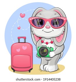 Cute cartoon rabbit in pink glasses with camera and luggage. Vector illustration of a traveling animal on a blue background.