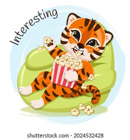 Cute cartoon striped red tiger happy  lying on a chair, eating popcorn and watching a movie. Funny baby tiger on blue background.