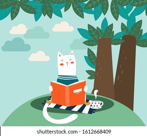 Cute cat reads a book under the tree. Funny animal relaxing in park
