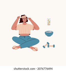Cute caucasian girl with sleeping mask and elements for morning routine: lemon water, weights, muesli. Girl thing about how to start her day. Woman in cute pajama. Good morning.