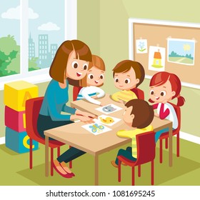 Cute children kids learning new words with flash cards in the class at primary school, pre-school. Teacher  teaches kids babies new words. Art classroom interior with pupils. Teacher with pupils.