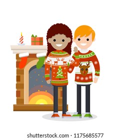A cute couple in red sweaters with a pattern celebrates new year and Christmas. Fireplace, candles and socks for gifts. Happy multicultural family and holiday. Deer and snow