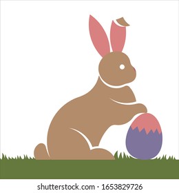 Cute Easter bunny logo, icon or illustration holding Easter egg and sitting on grass flat design