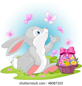 A cute Easter bunny sitting near Easter eggs basket.