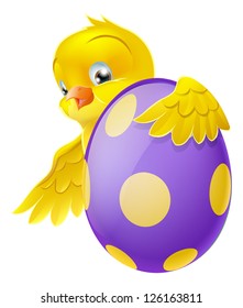 Cute Easter chick cartoon character holding onto and peeking round a painted chocolate Easter egg