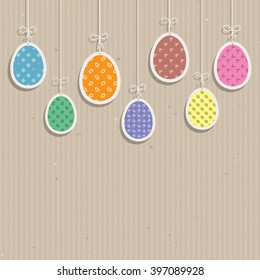 Cute Easter eggs hanging against a cardboard texture