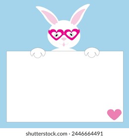 A cute Easter white rabbit in heart glasses with pink ears holds a white card with a heart. A place for your text