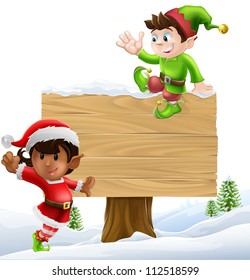 Cute elves one leaning on and one sitting on a Christmas sign in a winter landscape
