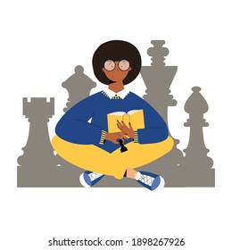 Cute girl with book and pawn in hands learn how to plays chess. Girl sitting cross legs with chess figures on the background. Girl reading chess exercise book and practicing chess game.