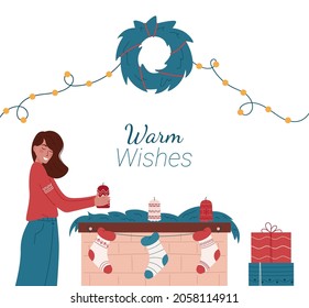 Cute girl decorating Christmas fireplace on light background. Caucasian woman holding candle. Christmas fireplace with candles, green decorations, socks and gifts.Warm Wishes. Merry Christmas