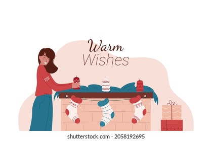 Cute girl decorating Christmas fireplace on light background. Caucasian woman holding candle. Christmas fireplace with candles, green decorations, socks and gifts.Warm Wishes. Merry Christmas