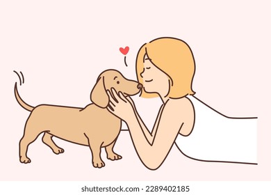 Cute girl kissing puppy enjoying communication with beloved pet and caring for dachshund during weekend. Schoolgirl teen lies on floor and plays with devoted puppy for animal friendship concept