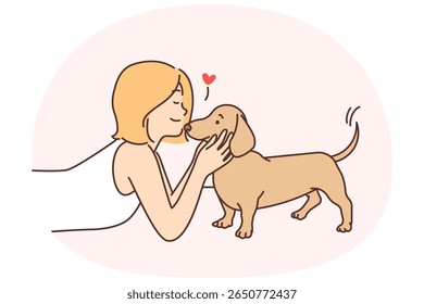 Cute girl kissing puppy enjoying communication with beloved pet and caring for dachshund during weekend. Schoolgirl teen lies on floor and plays with devoted puppy for animal friendship concept