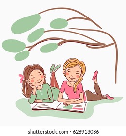 Cute girls reading a book under the tree