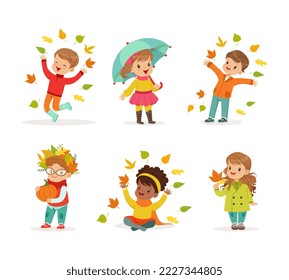 Cute kids in warm clothes walking outdoors in autumn season. Girl and boys standing under umbrella, throwing leaves cartoon vector illustration