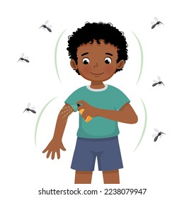 Cute little African boy applying insect repellent spray to his arm as protection against mosquitoes