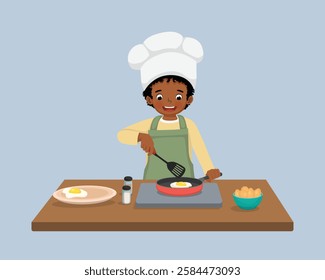 Cute little African boy chef cooking delicious fried egg with frying pan in the kitchen