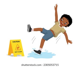 Cute little African boy having accident slipping on wet floor and falling down near yellow caution sign