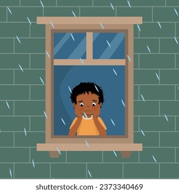 Cute little African boy looking at raindrops from window feeling sad can not play outside