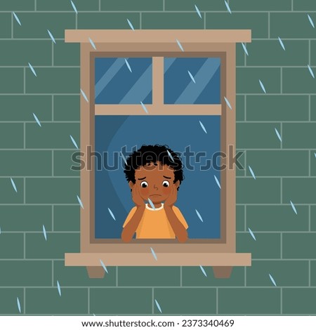 Cute little African boy looking at raindrops from window feeling sad can not play outside