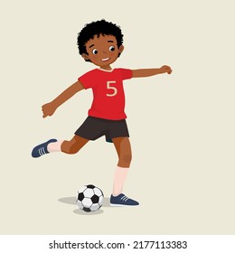 cute little African boy playing soccer kicking the football to make a goal