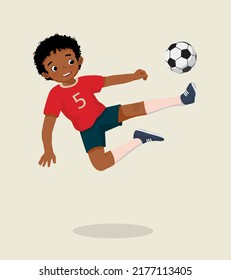 cute little African boy playing soccer jumping high kicking the football to make a goal