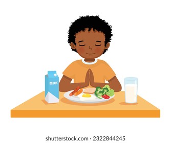 Cute little African boy praying before eating breakfast at the table